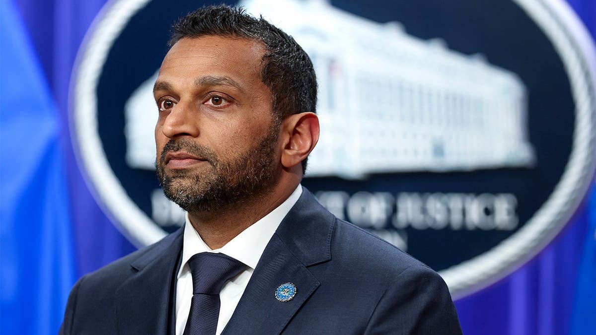 FBI Director Kash Patel listens during DOJ press conference on charges.