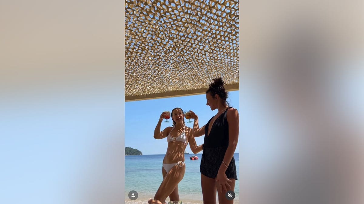 Kate Hudson and a friend in bikinis drinking a beverage.