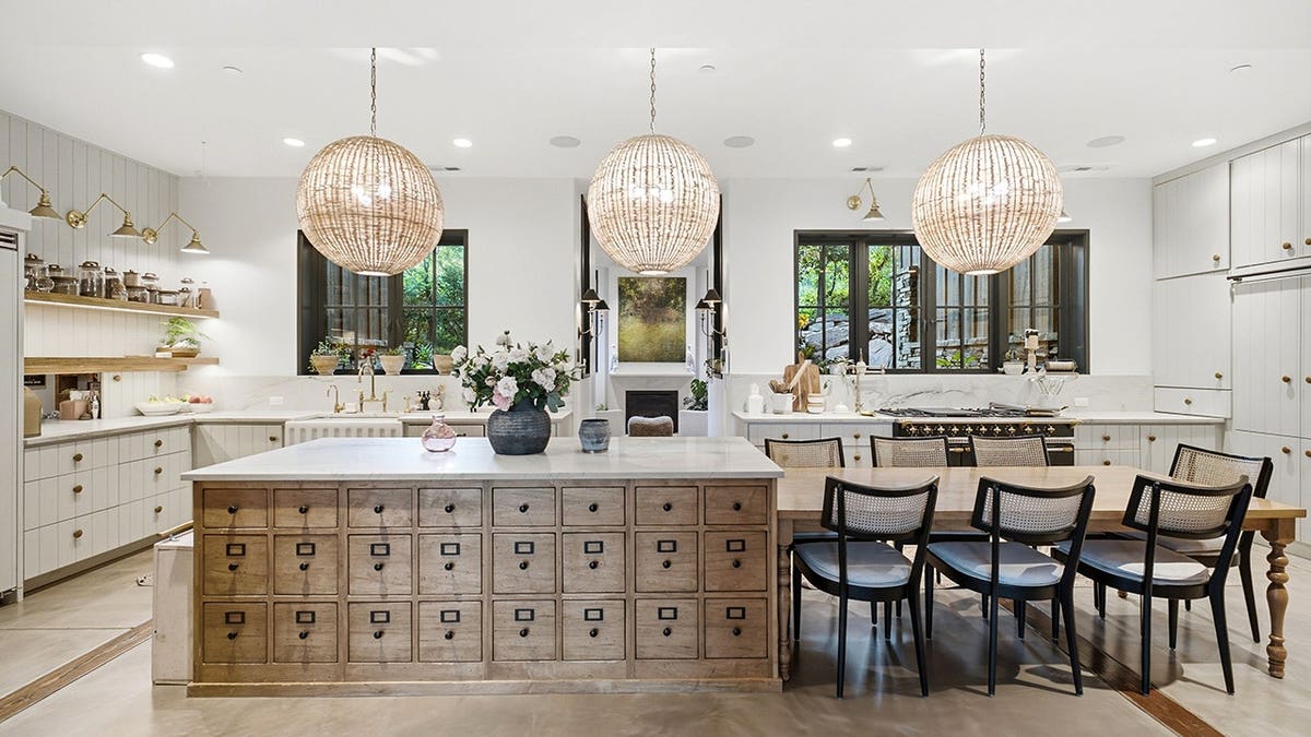 A kitchen with a large center kitchen island and unique light fixtures.