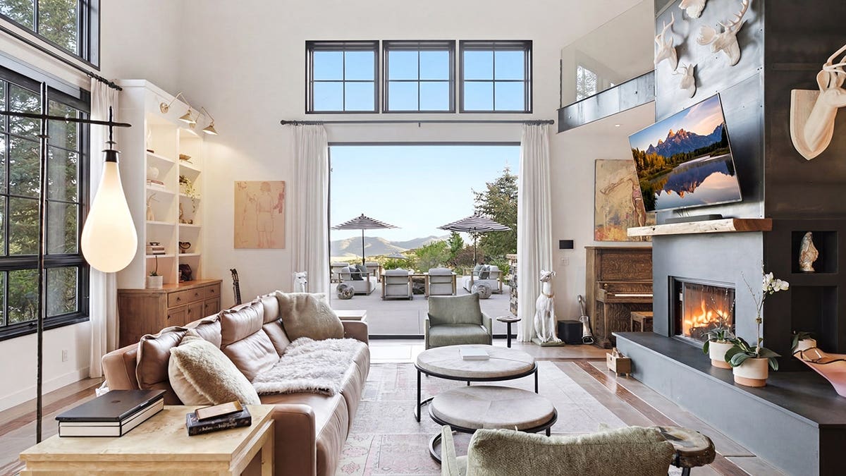 A living room with a large steel fireplace, big windows and access to the backyard.