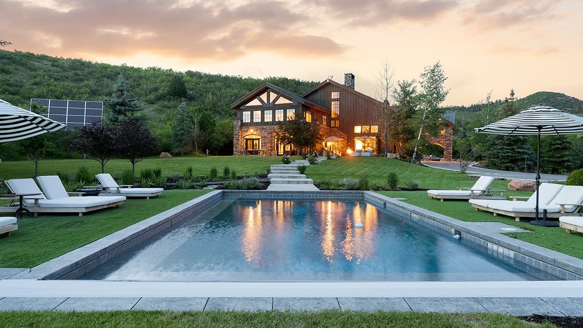 A swimming pool surrounded by manicured lawns, with the home in the background.