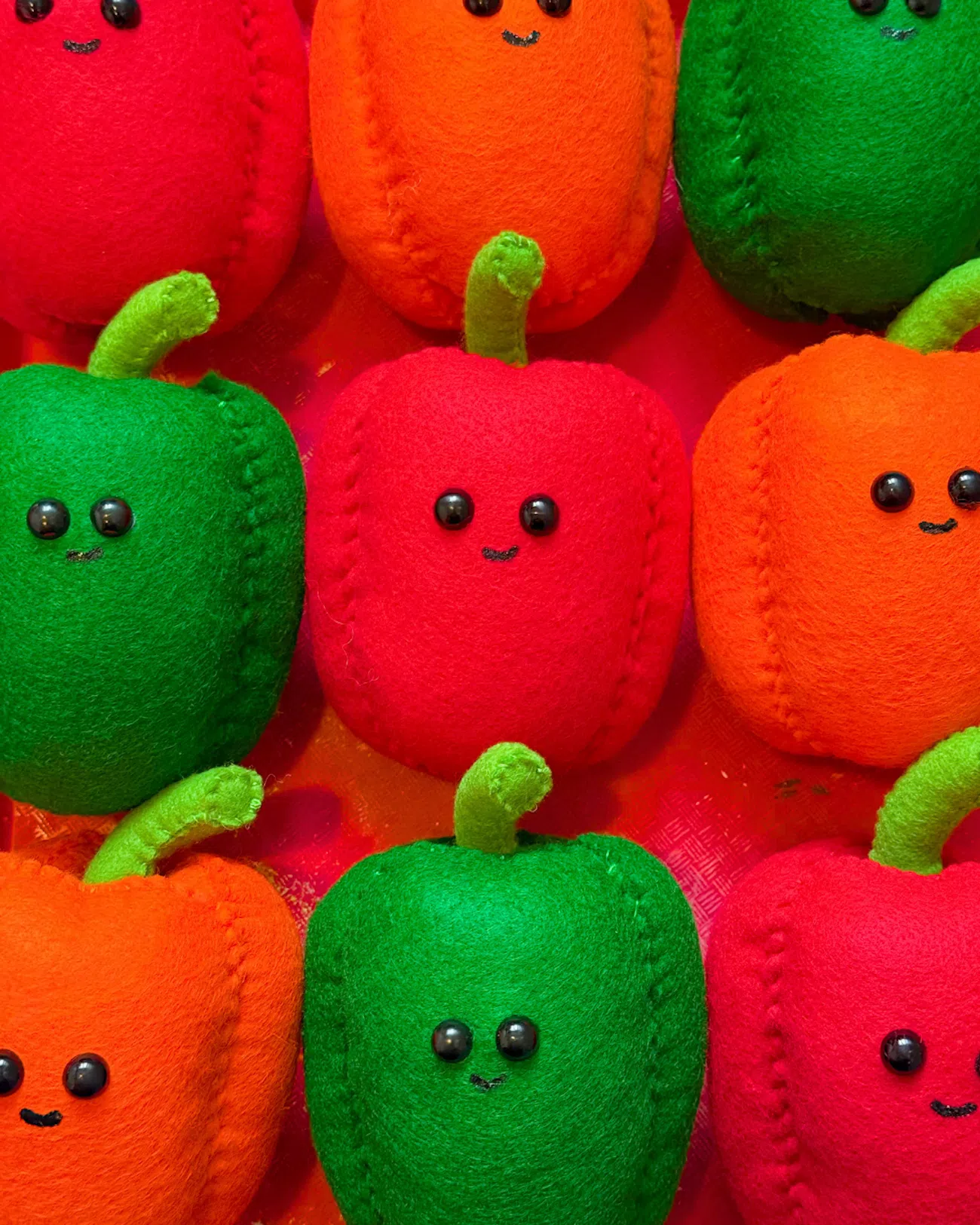 Bell peppers with little faces reimagined in felt by artist Lucy Sparrow