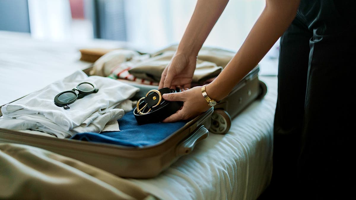 A woman folds clothes into a suitcase.