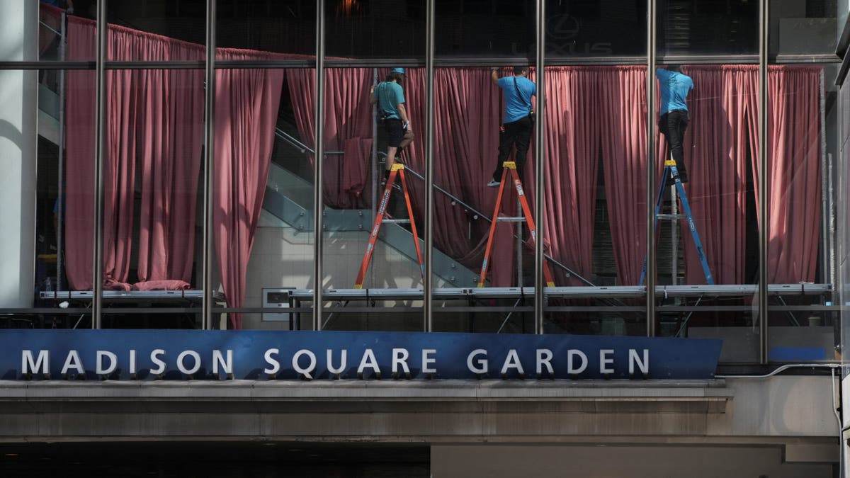 Workers hang up red curtains to block the windows at Madison Square Garden ahead of Taylor Swift and Travis Kelce's rumored wedding