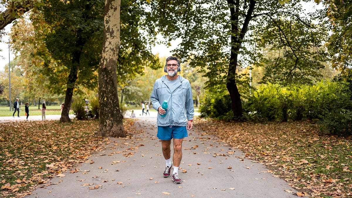 Older man walking along path in forest