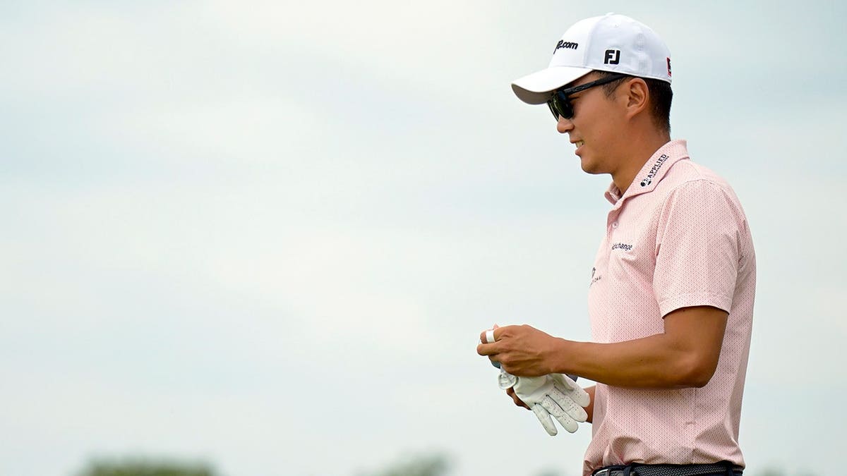 Michael Kim walks to his ball after hitting a tee shot on the golf course.