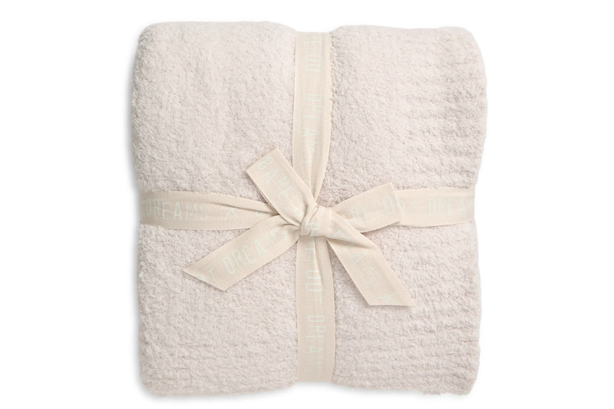 Folded cream-colored blanket tied with a cream ribbon with "BAREFOOT DREAMS" written on it.