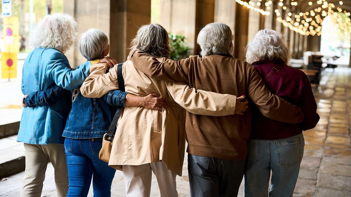 A group of senior citizens embraces and walks together.