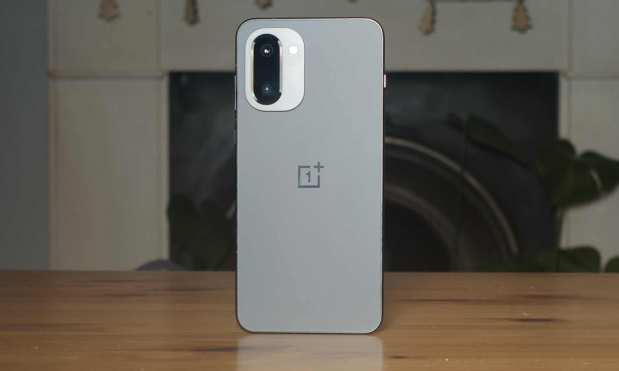 The rear of the OnePlus 15R, propped up on a wooden table.