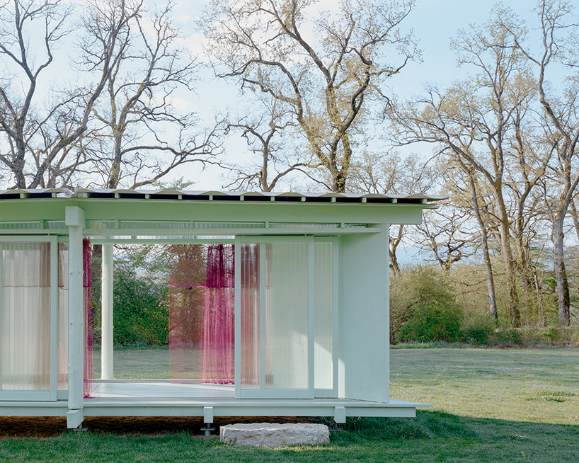 sliding timber frames and reused materials shape reversible pavilion within swiss meadow - 3