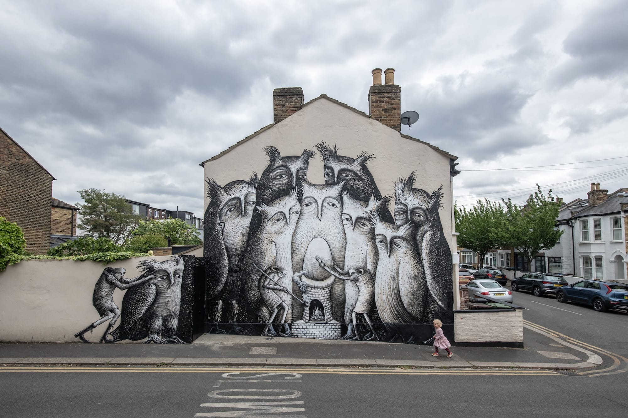 a mural by Phlehm on the side of a building featuring a group of owls standing around a glowing egg