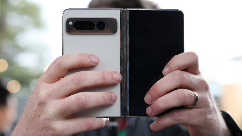 A person holding a foldable phone, with a focus on the camera