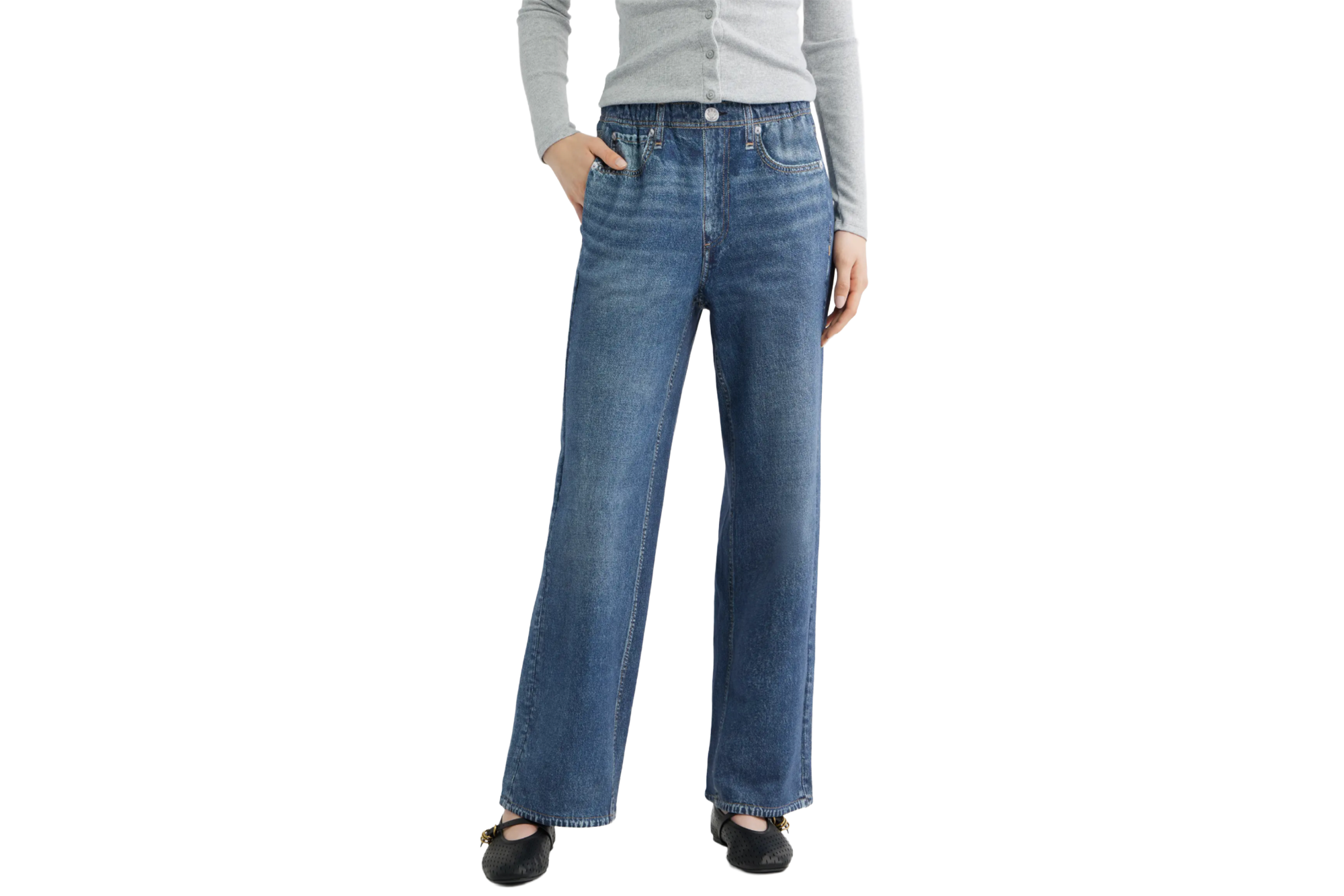A person wearing wide-leg jeans, a gray sweater, and black flats.