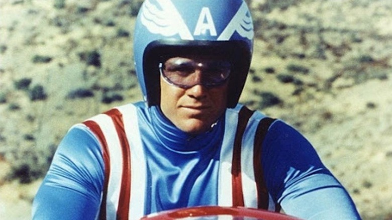 Reb Brown is astride a motorcycle as Steve Rogers in Captain America