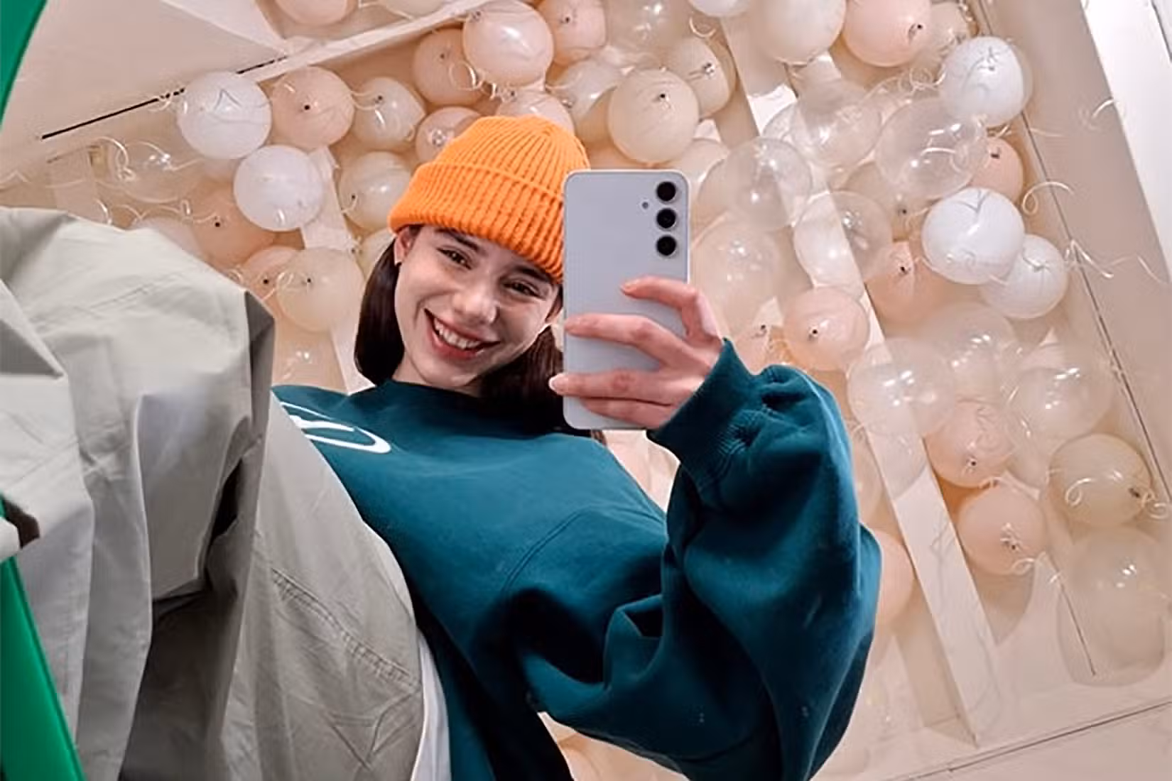 A young woman smiling while taking a selfie with the Samsung Galaxy A35 smartphone.
