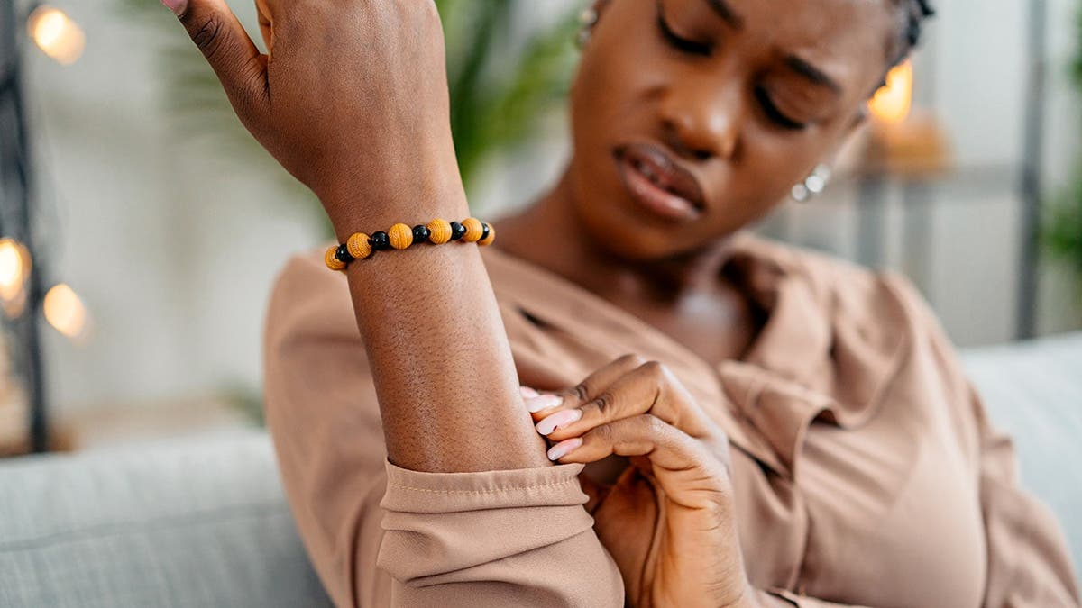 A woman scratches an itch on her arm.