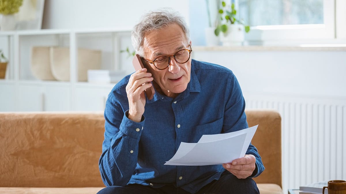 senior man on phone holding papers