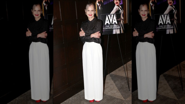 Elizabeth McGovern in a black top and white skirt with red shoes at an event