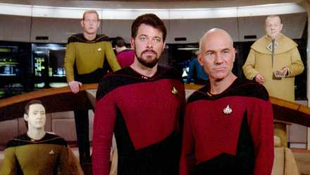 Riker and Picard standing on the bridge with Data and Kolrami behind them in Star Trek: The Next Generation