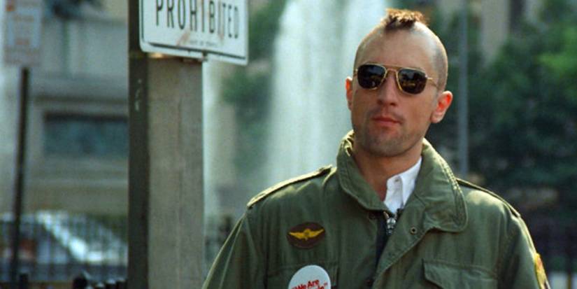 Travis Bickle (Robert De Niro) stands in a street in sunglasses and a rough mohawk in 'Taxi Driver' (1976).