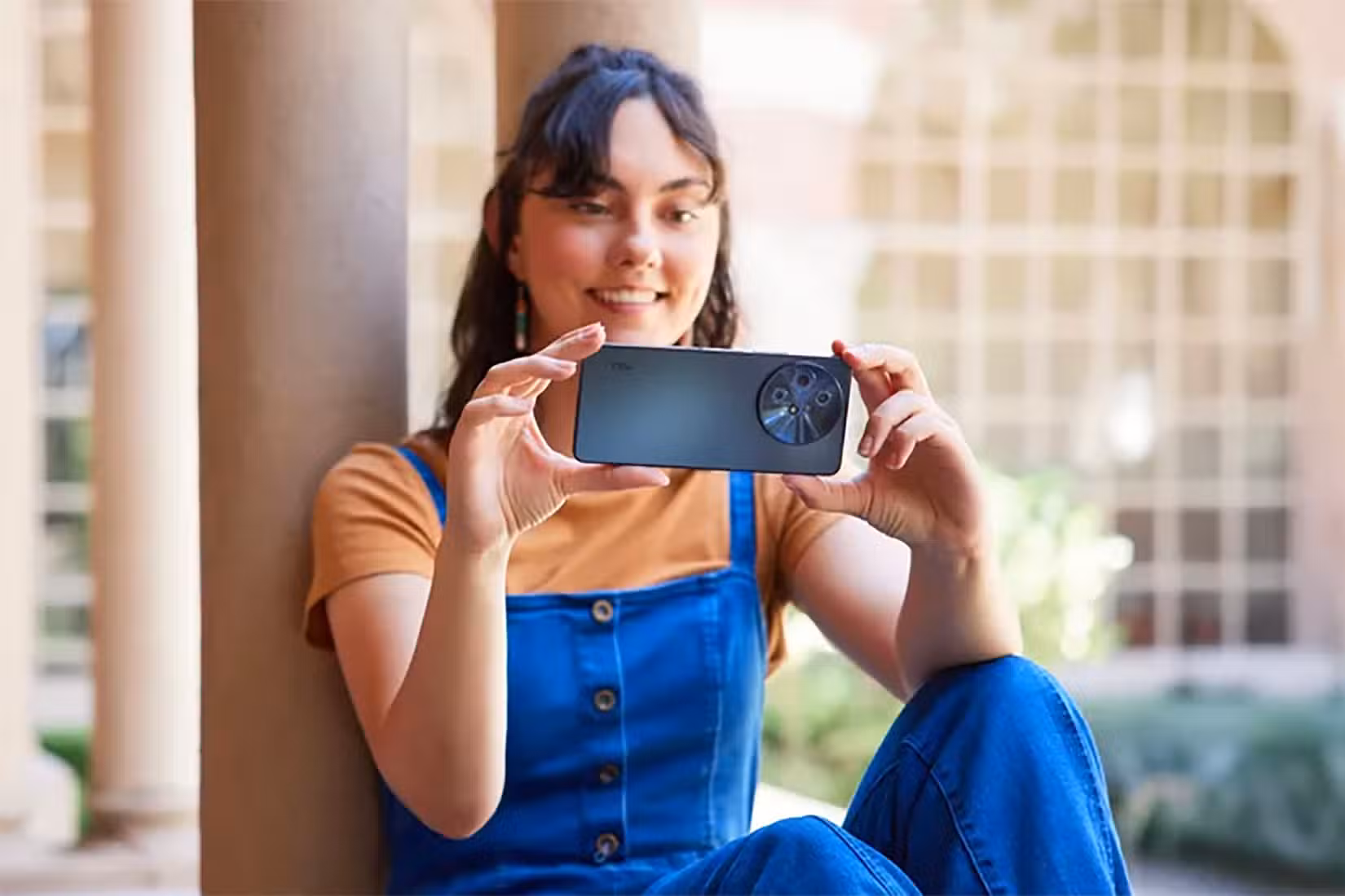 A woman sitting down holding the TCL 60 XE NxtPaper phone vertically.