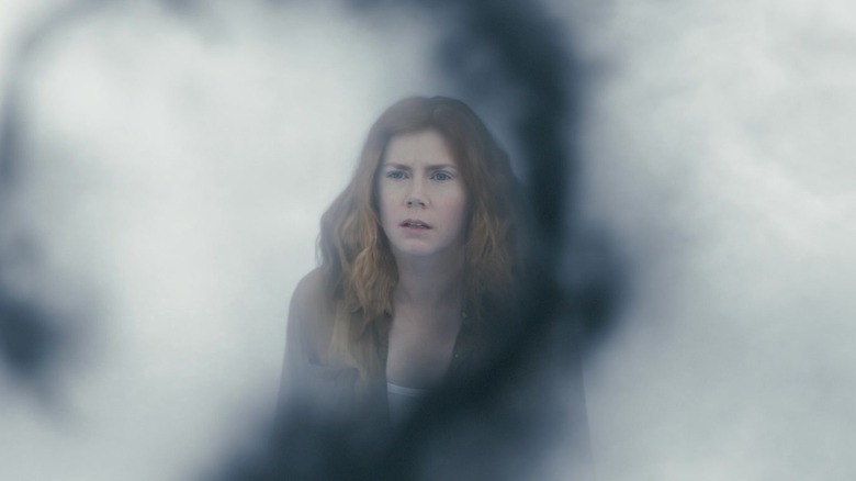 Louise in a smoky place looking at an alien glyph in Arrival