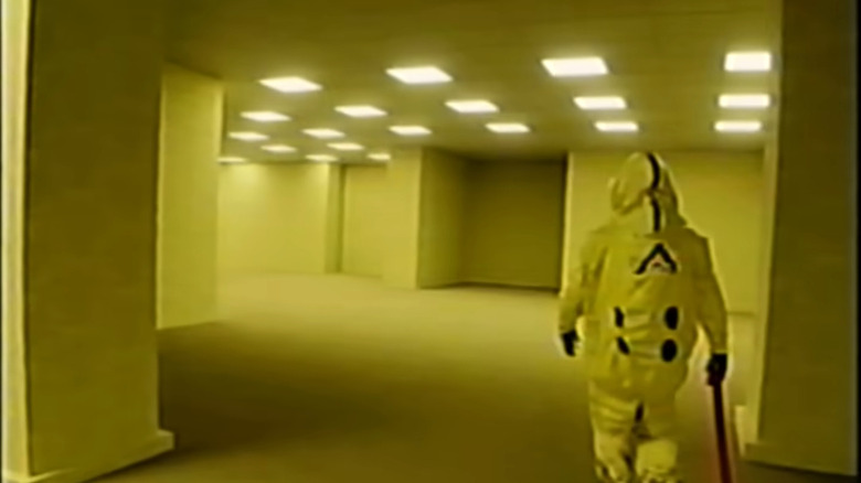 A man in a hazmat suit walks through The Backrooms.