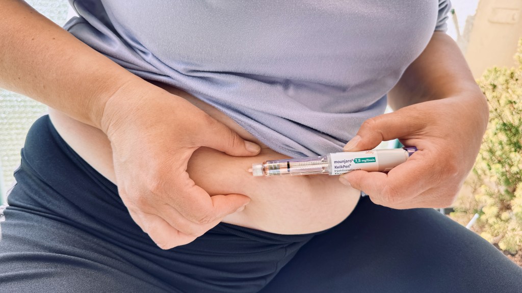 Woman injecting a Mounjaro KwikPen into her abdomen for diabetes and weight loss therapy.