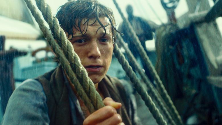 Tom Holland as Thomas standing in the rain on the boat in In the Heart of the Sea
