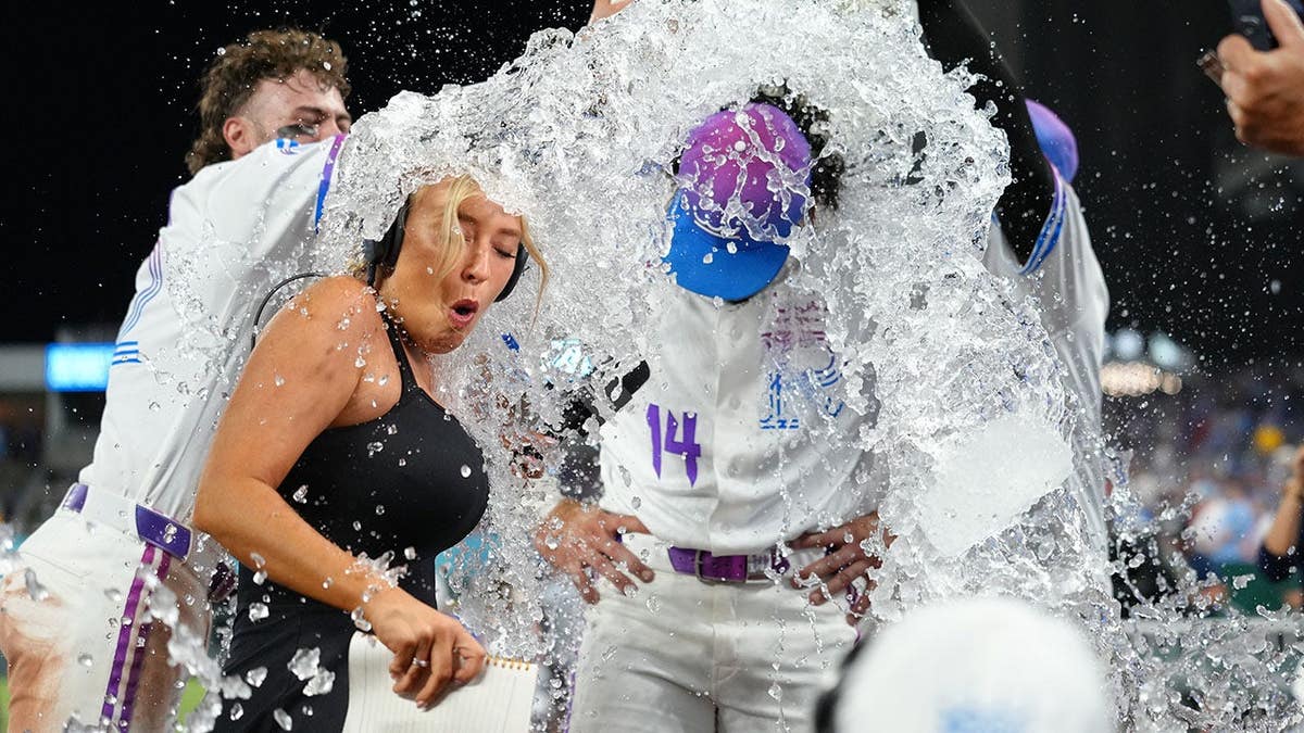 Tricia Whitaker and Jac Caglianone getting doused with water on the field.