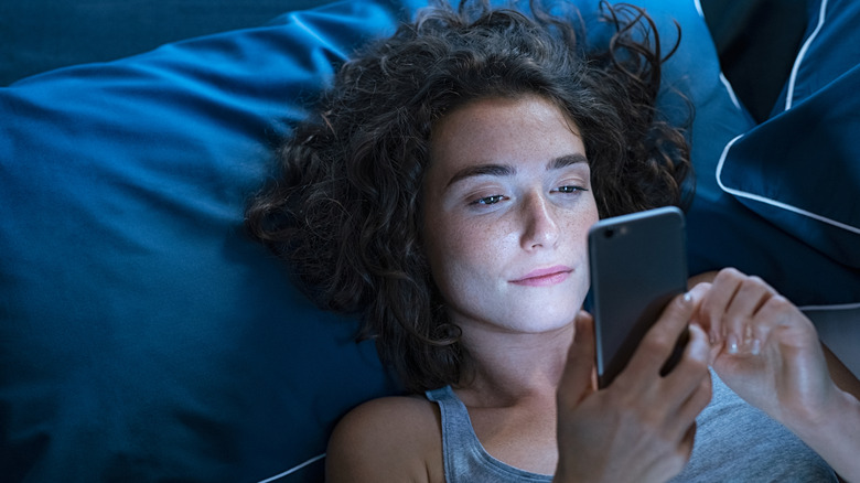 A woman using a phone in bed