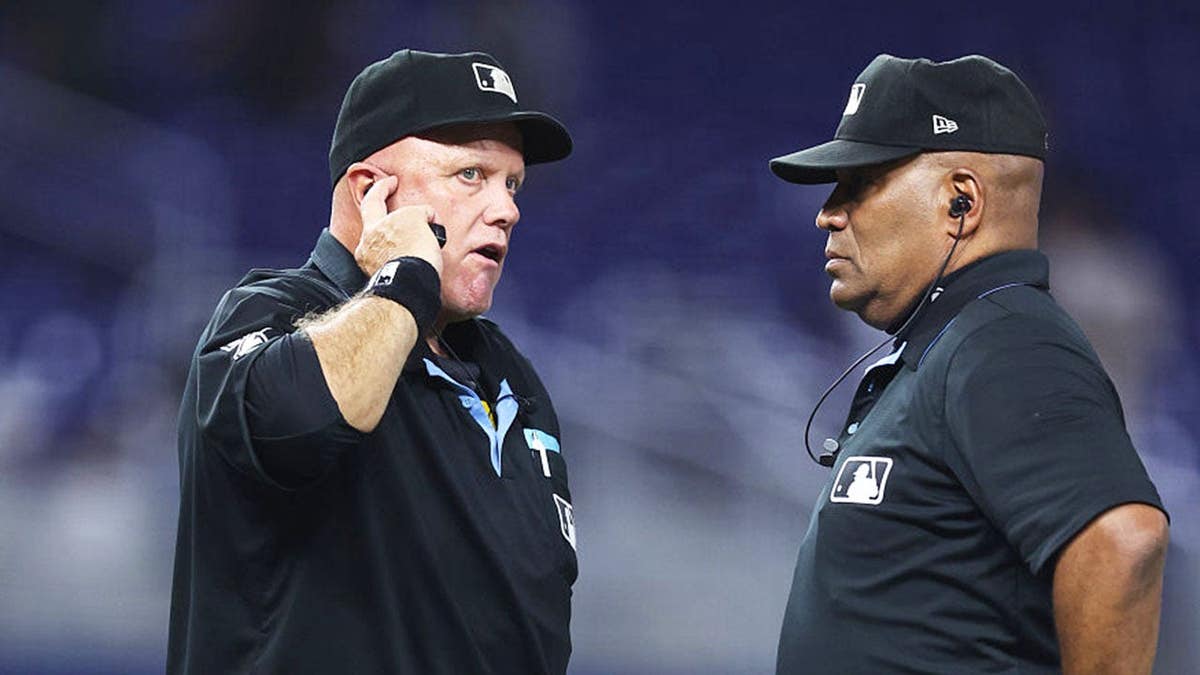 Umpires Brian O'Nora and Laz Diaz speak on the field at loanDepot park.