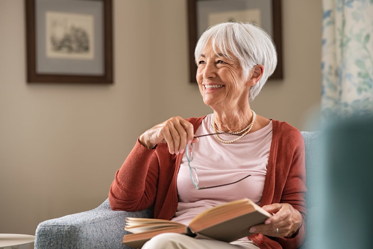 A smiling person holding a book.