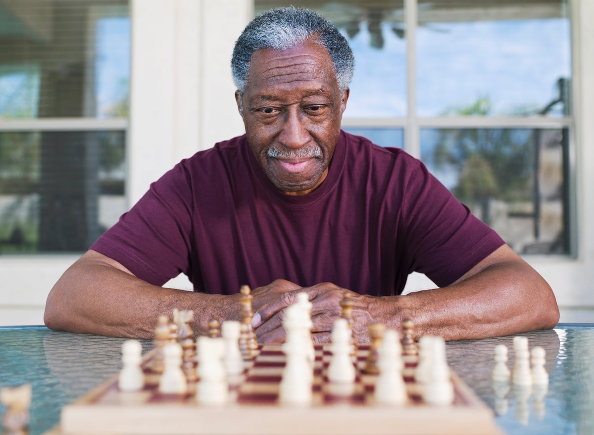 A person sitting in front of a chess board contemplating game strategy.
