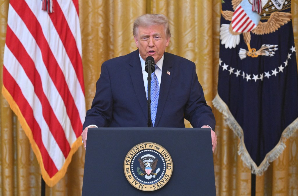 Donald Trump speaking from a podium with the Seal of the President of the United States.