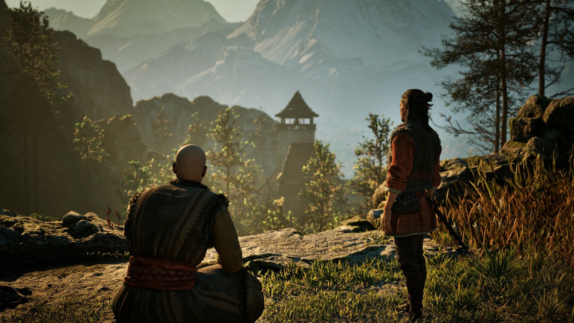 Two people sit on a hillside.