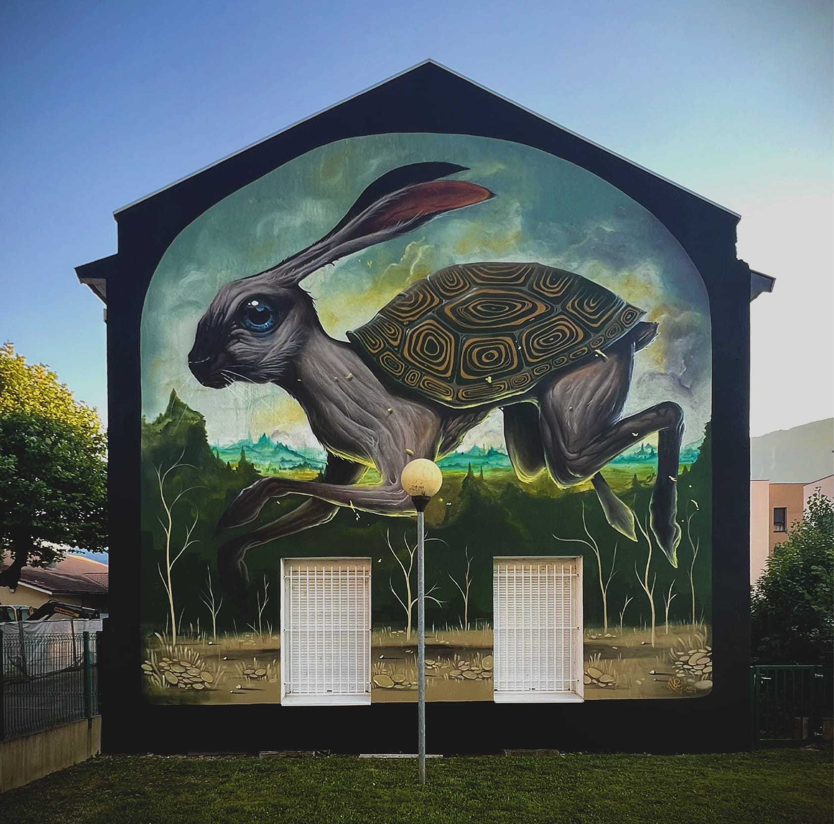 a large mural on the side of a building of a skinny hare with a tortoise shell
