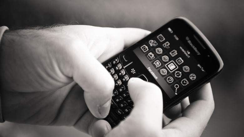 Black-and-white photo of hands holding a BlackBerry Phone