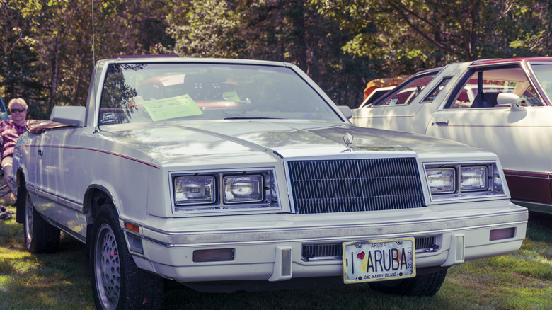 A white Chrysler LeBaron parked on grass.