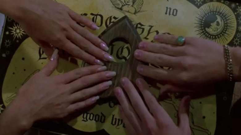 Four hands on a oujia cloche in Witchboard