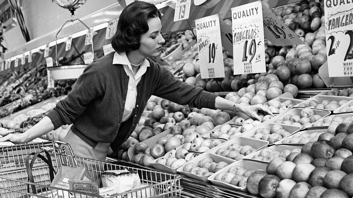 Woman picks through produce in a supermarket.