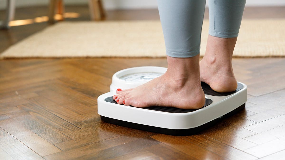 Woman stands on a scale checking her weight.