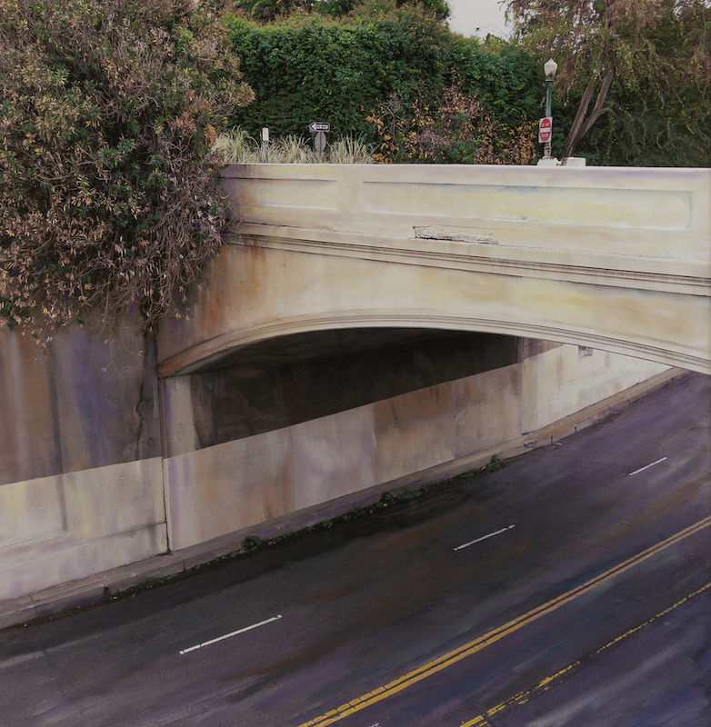 A sunlit road curves beneath a concrete overpass edged by trees and flowers, © Ann Mitchell.
