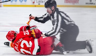 Mar 16, 2026; Detroit, Michigan, USA; Detroit Red Wings center Mason Appleton (22) and Calgary Flames center Connor Zary (47) are broken up by linesman Scott Cherrey (50) during the second period at Little Caesars Arena. Mandatory Credit: Tim Fuller-Imagn Images