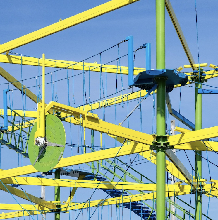 Lime-green beams, cables, and suspended components of an amusement ride form a dense pattern against a vivid blue sky. ©CynthiaGladis