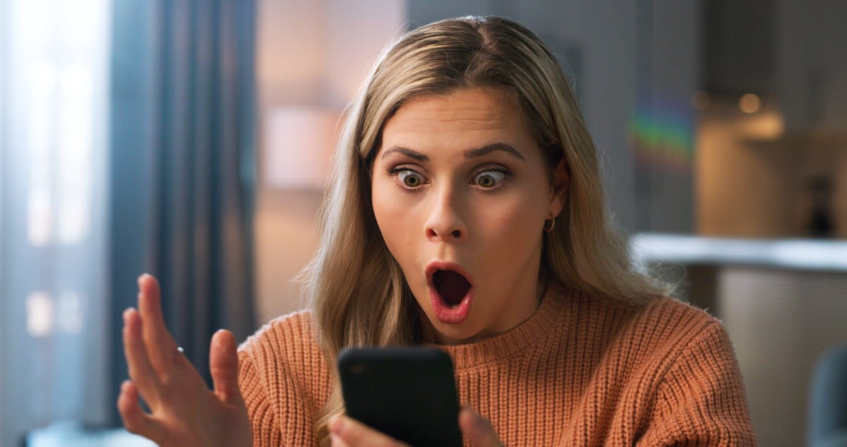 surprised investor looks at smartphone.