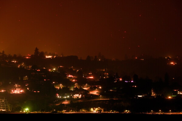 Hot spots from the Bald Range wildfire burn on the mountainside above houses in Summerland, British Columbia, late Saturday, Aug. 8, 2026. (Darryl Dyck/The Canadian Press via AP)