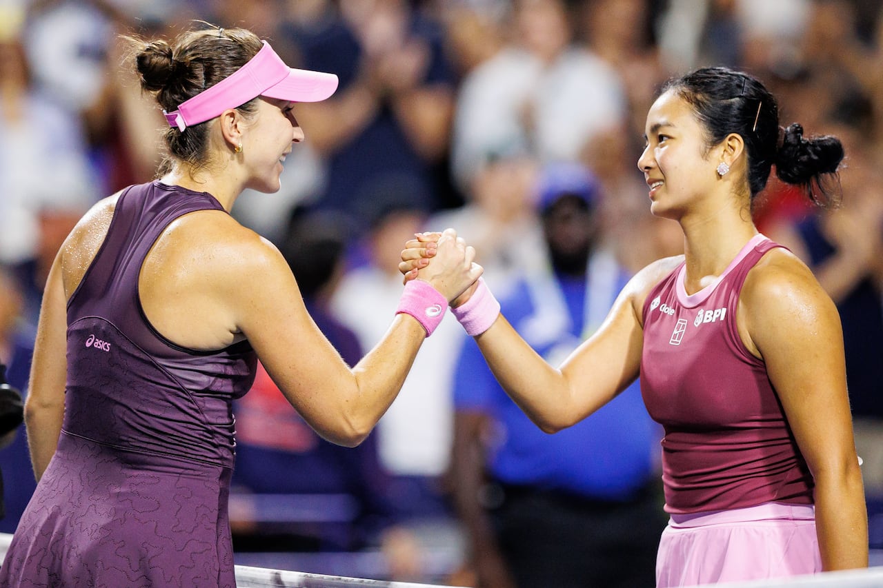 Two female tennis players shake hands at the net.