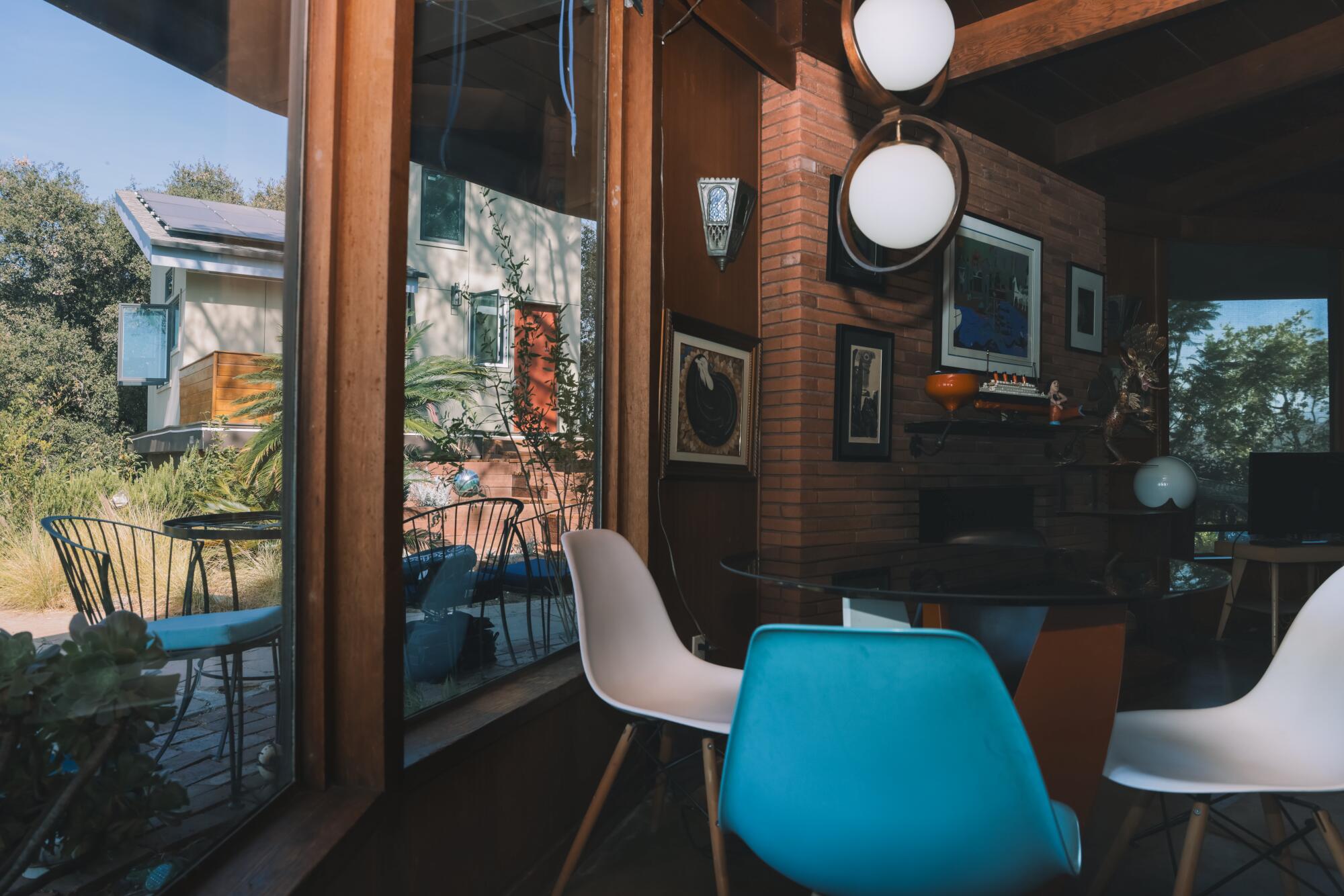 A view of an ADU from inside a dark midcentury home with a red brick fireplace.