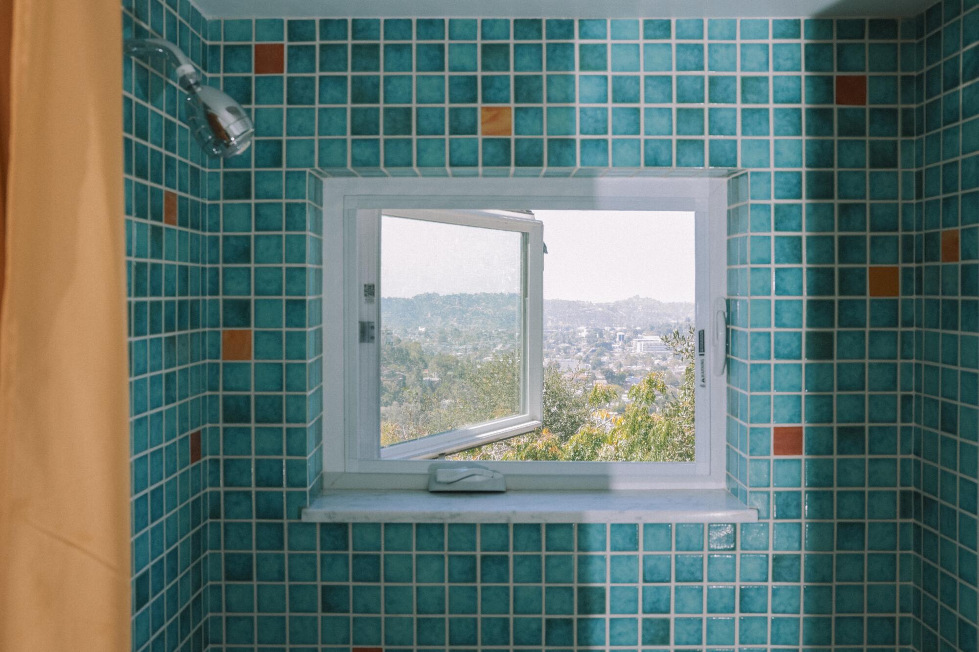 A window in a blue tiled shower looks out over Los Angeles.